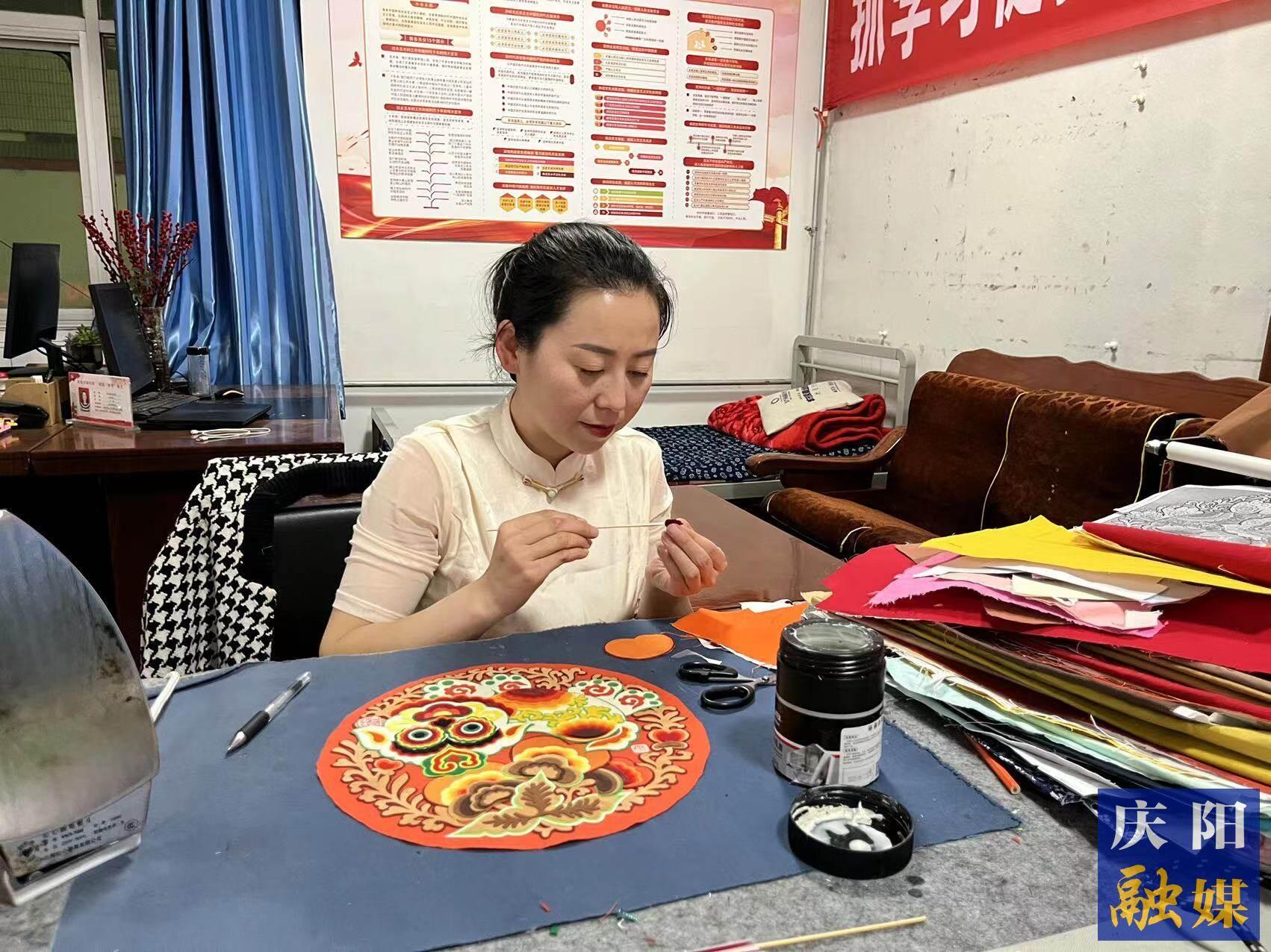李慶英正在創(chuàng)作布貼畫(huà)作品。